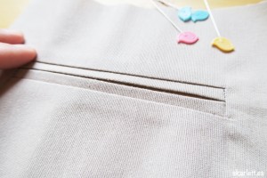 detalle de bolsillo ribeteado acabado con alfileres de colores con forma de pajaro